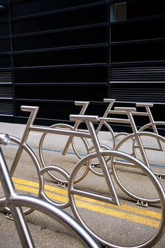 Across the foreground, bicycle racks repeat in angled lines, turning metal geometry into empty parking beside the urban facade of Oslo, Norway under daylight