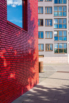 Sunlight throws a long shadow over a brick wall, while geometry guides the courtyard in Stockholm and red contrast leads toward a facade elsewhere in Sweden
