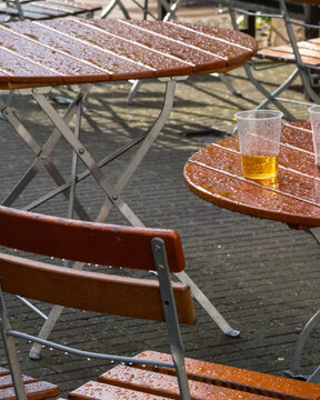 Tables and chairs with drinks after rain at an outdoor cafe in the afternoon sun