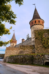 Kamianets-Podilskyi, Ukraine, june 23, 2026 A low-angle view of the iconic towers of the Kamianets-Podilskyi castle fortress under a soft blue evening sky. © Olena
