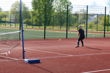 Fototapeta premium Man Playing Tennis on Outdoor Red Court During Sunny Day - Active Lifestyle and Sports Concept