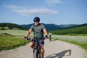 Fototapeta premium Active senior biking in nature, wearing helmet and sunglasses.