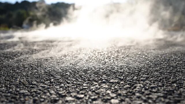 Steam Rising from Sunlit Asphalt Road Surface
