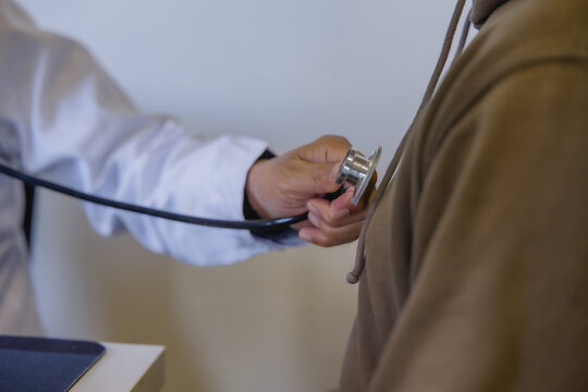 Doctor examining patient with stethoscope during routine medical checkup in a modern clinic. Healthcare, physical examination, preventive medicine