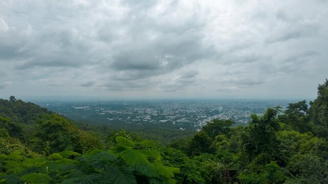 Horizontal timelapse footage of a panoramic mountain viewpoint overlooking a tropical forest and expansive city skyline beneath dramatic moving clouds. Ideal for travel, tourism, weather, nature