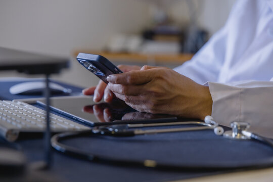 Doctor using smartphone to access patient information in a modern clinic. Mobile healthcare healthcare technology and connected care.