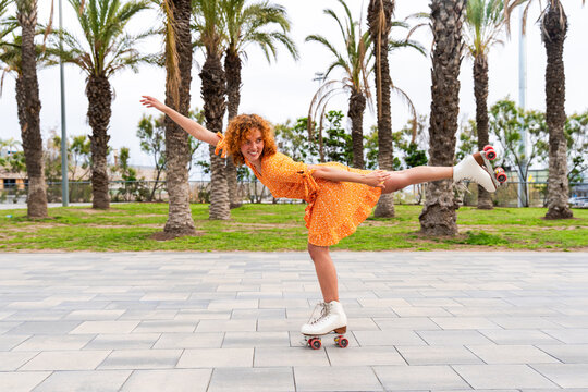 Beautiful red haired young woman with rollerskates having fun outdoors