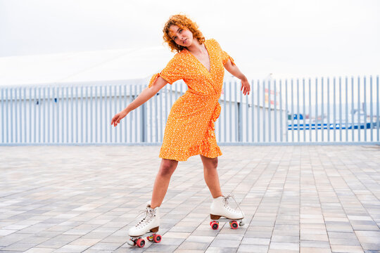 Beautiful red haired young woman with rollerskates having fun outdoors