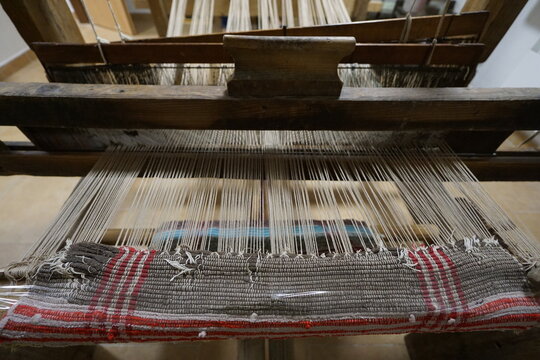 Close-up of a traditional wooden handloom weaving a patterned textile, showcasing heritage craftsmanship, textile production, folk art, and traditional craft techniques.