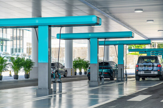 Modern electric vehicle charging station with multiple cars connected to chargers in parking area, Shenzhen, China. Clean transportation infrastructure, sustainable mobility, green technology