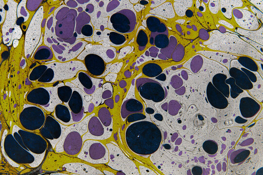 Abstract Ebru marbled paper pattern with yellow, purple and black fluid art drops for background design and creative texture.