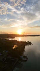 Fototapeta premium Vertical aerial sunrise over a tropical bay and island coast