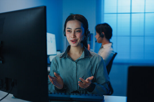 Gen z Asia young call center team or customer support service executive use computer and microphone headset work technical e commerce support in late night office. Telemarketing or sales job concept.