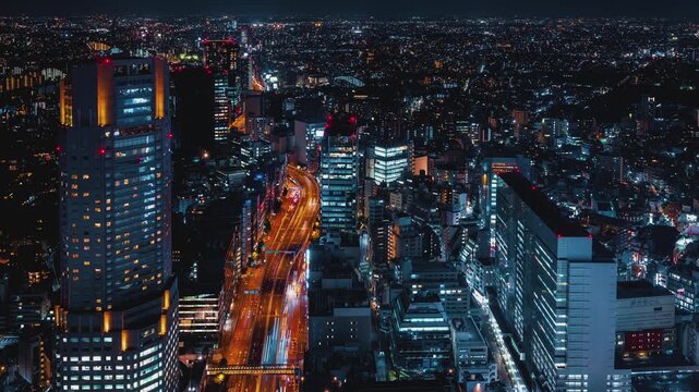 Shibuya City Night Skyline Timelapse Aerial View of Busy Urban Expressway with Vibrant Vehicle Light Trails Flowing Through Modern Skyscrapers and Glowing Office Buildings 4k