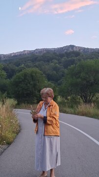 woman with a bouquet of wild flowers by the road in the mountains