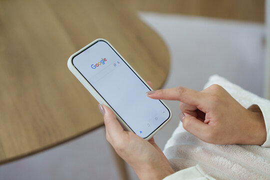July 23, 2026: A woman's hand is touching screen on tablet iphone at night for searching on Google search engine. Google is popular Internet search engine