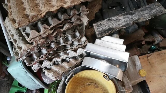 A disorganized collection of household items including cardboard egg cartons and metal kitchen tools.