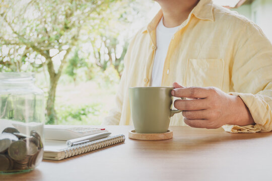 Relaxed Morning Financial Planning with Coffee Savings Jar Calculator and Notebook on Wooden Desk at Home Natural Lifestyle Budget Management Personal Finance Habit and Mindful Money Organization