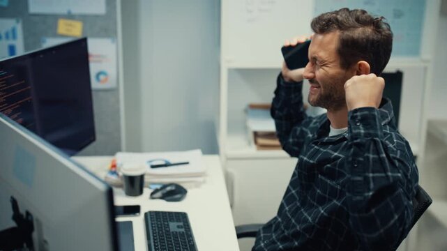 Young Caucasian male developer use mobile phone while working with multiple monitor in office. Professional AI developer workspace, Secure computer network system, Advanced cybersecurity data concept.
