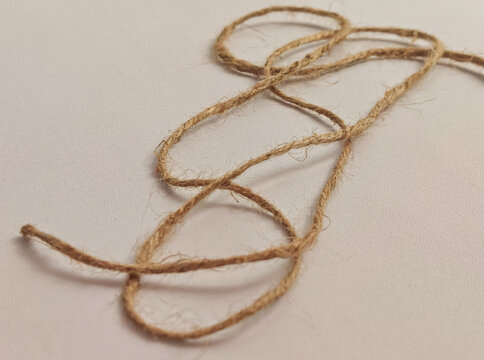 Natural jute twine rope arranged on a white background showing organic fiber texture, handmade material details, rustic craft concept, and minimal neutral composition suitable for packaging, design