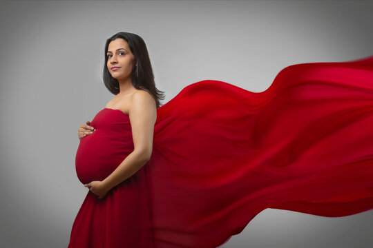 Pregnant woman holding her baby bump in a dress.