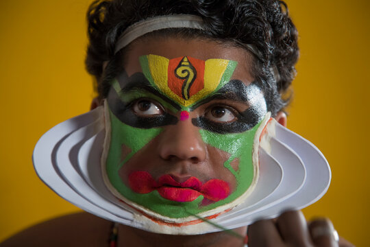 Kathakali dancer giving a touch up on his face.