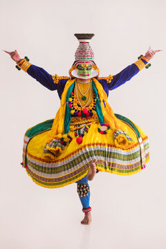 Kathakali dancer standing in front of a white background showing a mudra. 