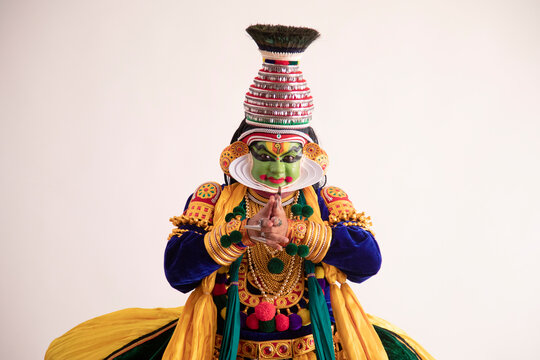Kathakali dancer dancing in front of a white background.