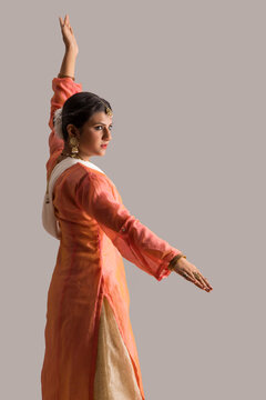 Beautiful kathak dancer performing through her expressions over a plain background. 