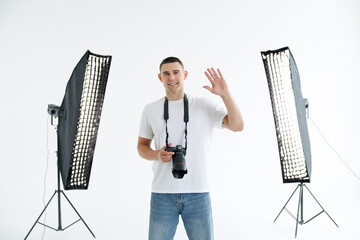 Young man photographer in studio wave greetings isolated on white background © F8  \ Suport Ukraine