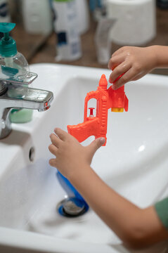 Bright bathroom scene with a child playing with a water gun in summer light