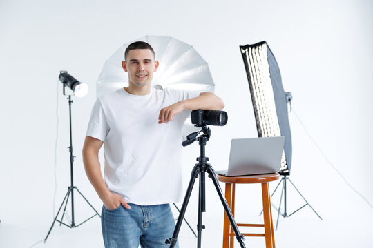 Positive guy holding digital camera, professional photographer enjoying his job at photostudio