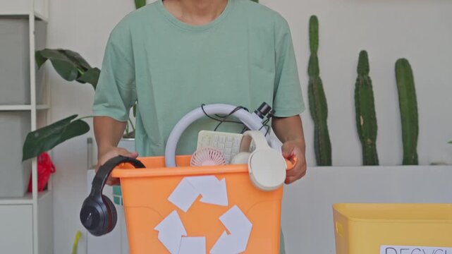 Close up of person presenting bin full of old electronics and tech devices for recycling