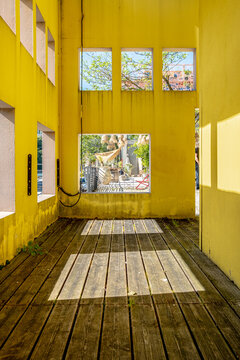 Inside a yellow corridor in La Confluence, Lyon, France, windows channel sunlight and shadows across the floor, extending perspective through the architecture
