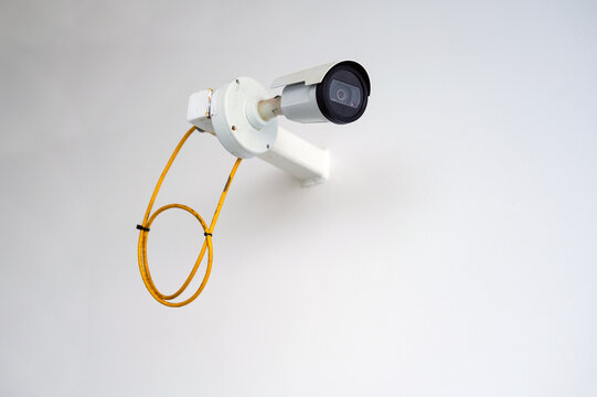 Konzept Security: Seitenansicht auf eine an eine wei&szlig;e Wand montierte Sicherheitskamera oder &Uuml;berwachungskamera im Au&szlig;enbereich mit viel Copy Space, selektive Sch&auml;rfe