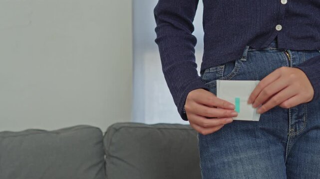 Woman pulling wrapped sanitary pad out of her jeans pocket for menstrual hygiene care