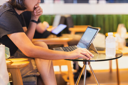 Side view of a thoughtful woman working in co working lounge using laptop.