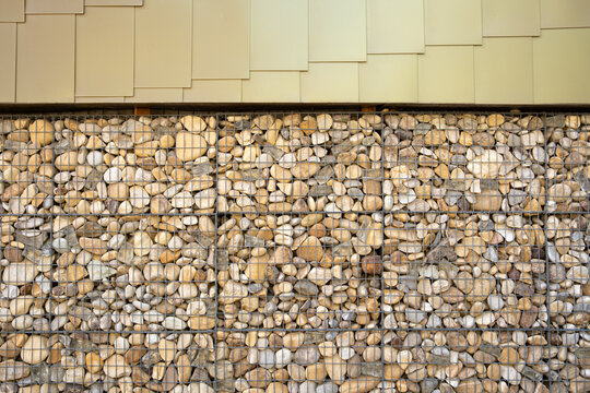 Facade detail in La Confluence, Lyon, France, pairs pebbles and cladding in a geometric pattern, turning architecture into a tactile study of texture