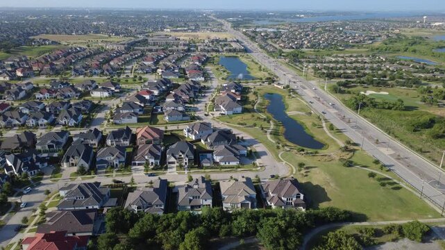 Expansive flat roof retail structures sit alongside residential enclaves in rapidly expanding Dallas Fort Worth metroplex. Neighborhood access roads thread through properties in Frisco, Texas