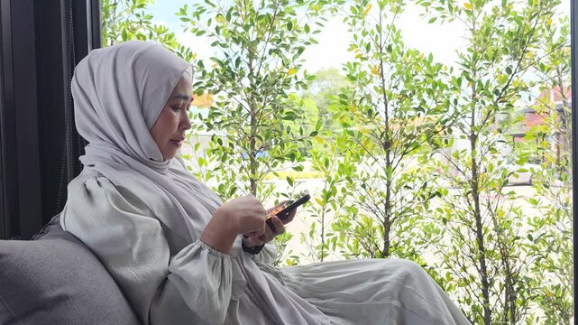 Muslim consumer focusing on smartphone interface showcasing modern digital connectivity and telecommunication technology