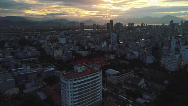 Da nang cityscape drone view at sunset with modern skyscrapers and residential buildings along the han river and distant mountains creating an urban skyline scene in vietnam