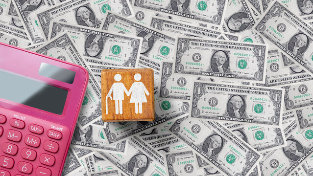 Flat lay of a pink calculator and a wooden block with an elderly couple icon on a background of US dollar bills, symbolizing retirement savings, pension planning, and financial management.
