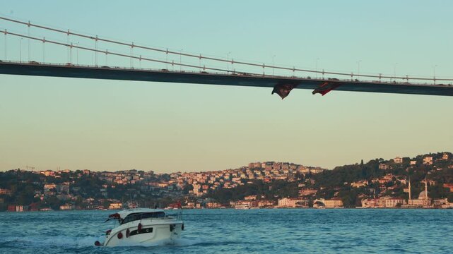 The Galata bridge in Istanbul -Turkey, two flags under the bridge and motorboat passing under the bridge