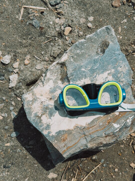 Diving mask lying on rock near water shore, summer beach recreation concept.