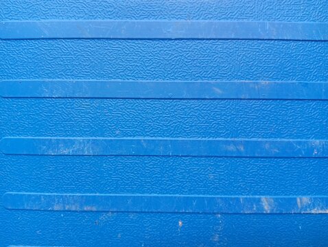 Top view of a closed blue hard plastic tool case or equipment storage container with textured surface lying on a gray concrete floor, suitable for industrial, construction, or DIY garage themes.
