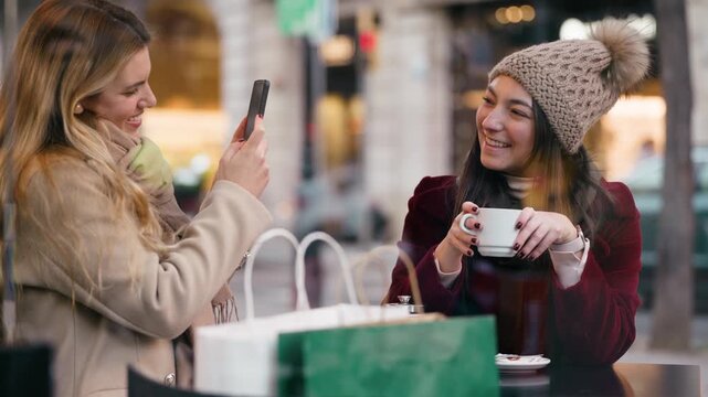 Video of one friend is taking a photo of the other while drinking coffee in the bar terrace.
