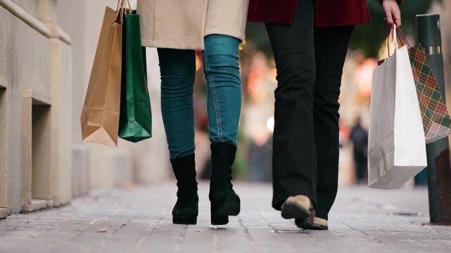 Video of close up of two friends walking on the city street with shopping bags.