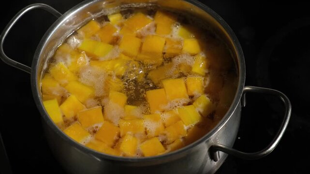 Cooking pumpkin puree soup. Pumpkin pieces in a boiling pot of water