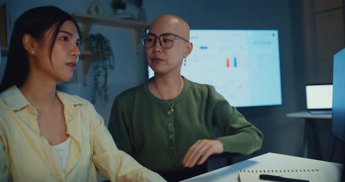 Young Asian businesswomen team meeting work on laptop at office night. Corporate teamwork collaboration, financial report analysis, strategy project planning, colleague development support concept.