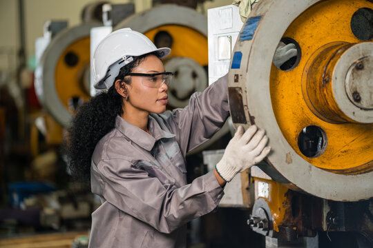 Woman Engineer Examining Worn Flywheel Surface On Vintage Metal Stamping Machine